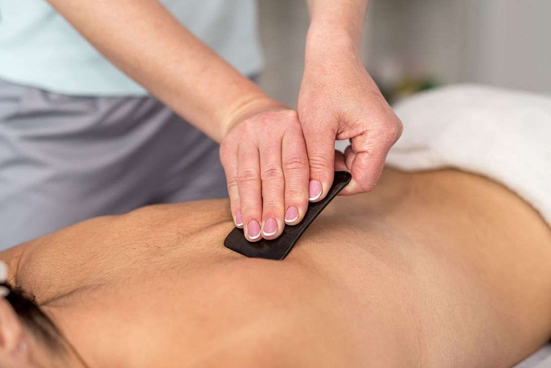 Massagetherapeut verwendet in einem Spa-Umfeld einen heissen Stein auf dem Rücken eines Kunden