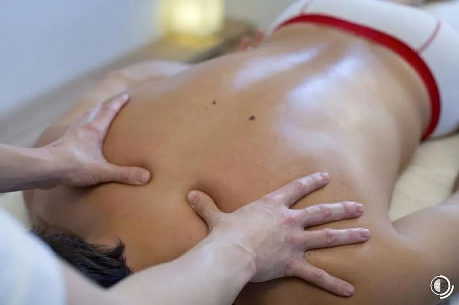 Eine Masseurin knetet während einer Spa-Behandlung den nackten Rücken eines Kunden.