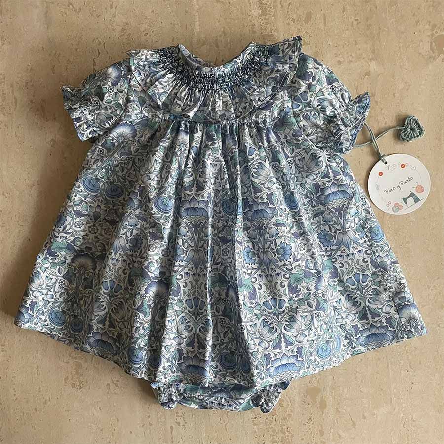 Vestido de bebé con estampado floral azul, cuello y mangas con volantes.