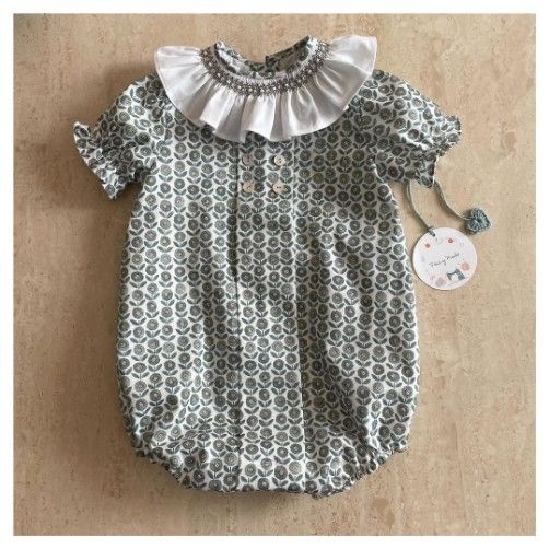 Mono para bebé con estampado floral, cuello con volantes blancos y etiqueta.