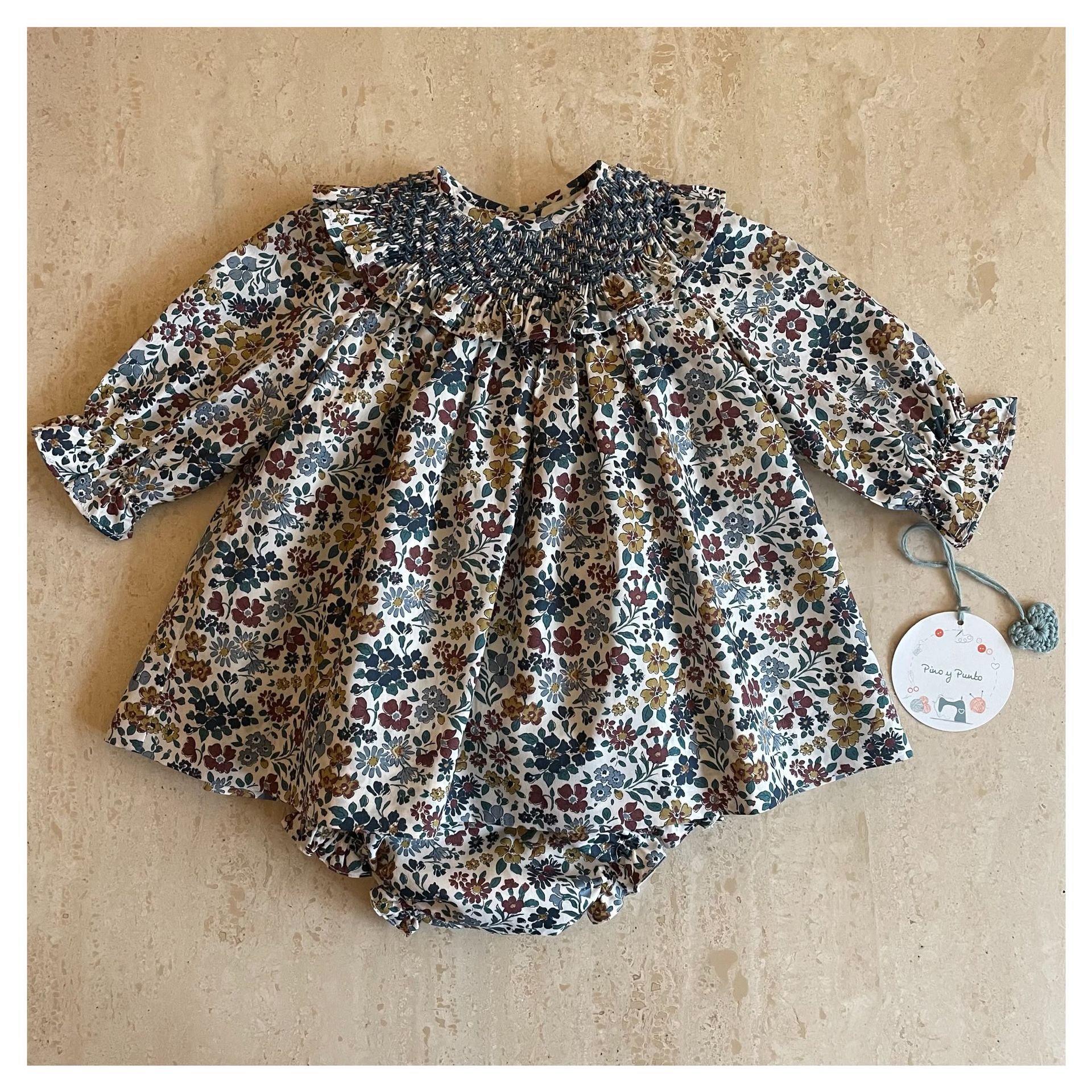 Vestido de bebé con estampado floral azul, cuello y mangas con volantes.