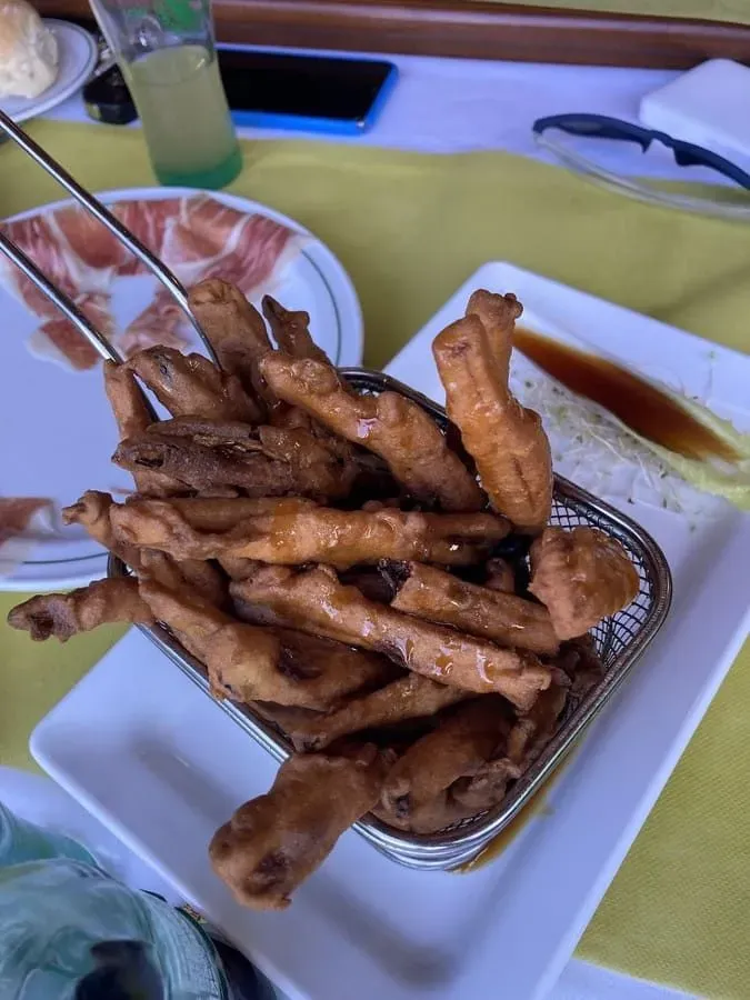Cesta de comida frita sobre una mesa, con platos de comida y bebida.