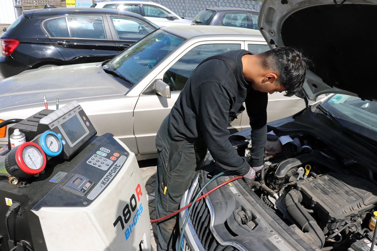 Ein Mechaniker arbeitet im Freien mit Diagnosegeräten an einem Automotor.