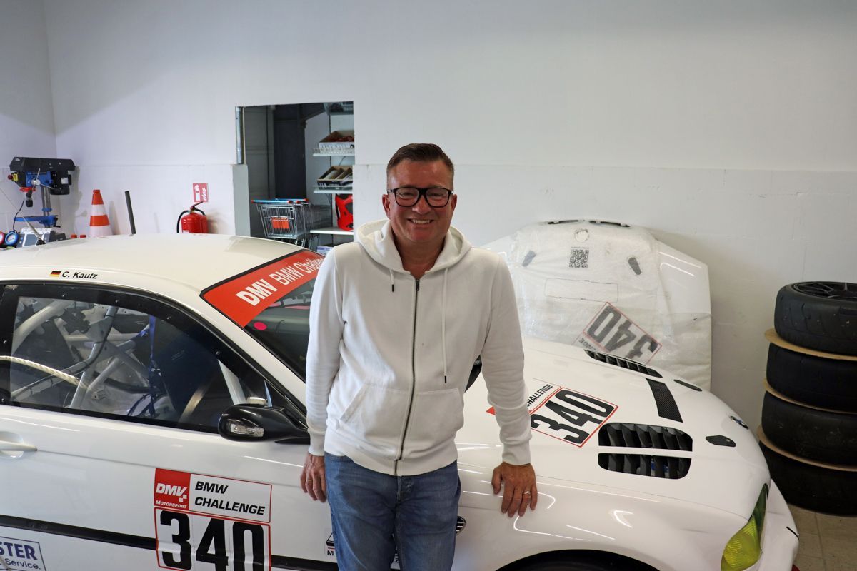 Mann vor einem weißen Rennwagen mit der Nummer 340 in einer Garage.