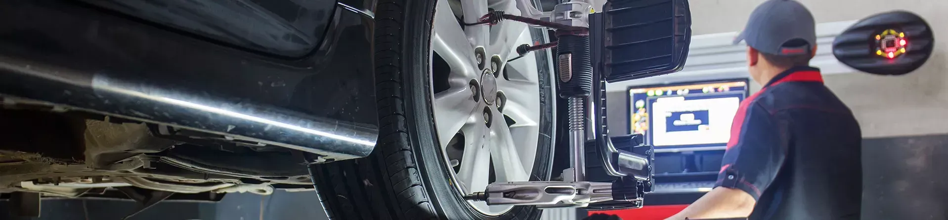 Ein Mechaniker in einer Werkstatt benutzt einen Computer, um ein Autorad auszurichten.