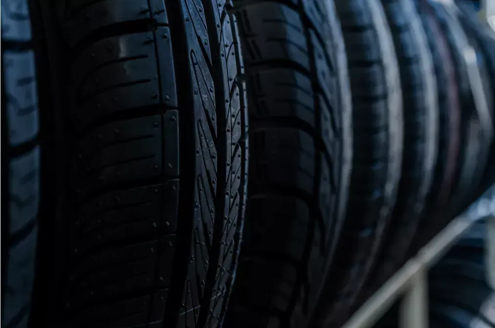 Nahaufnahme einer Reihe schwarzer Autoreifen mit tiefem Profil in einer Garage.