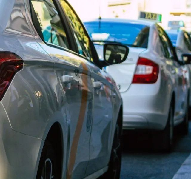 Cars lined up in traffic on a city street, with a silver sedan in the foreground
