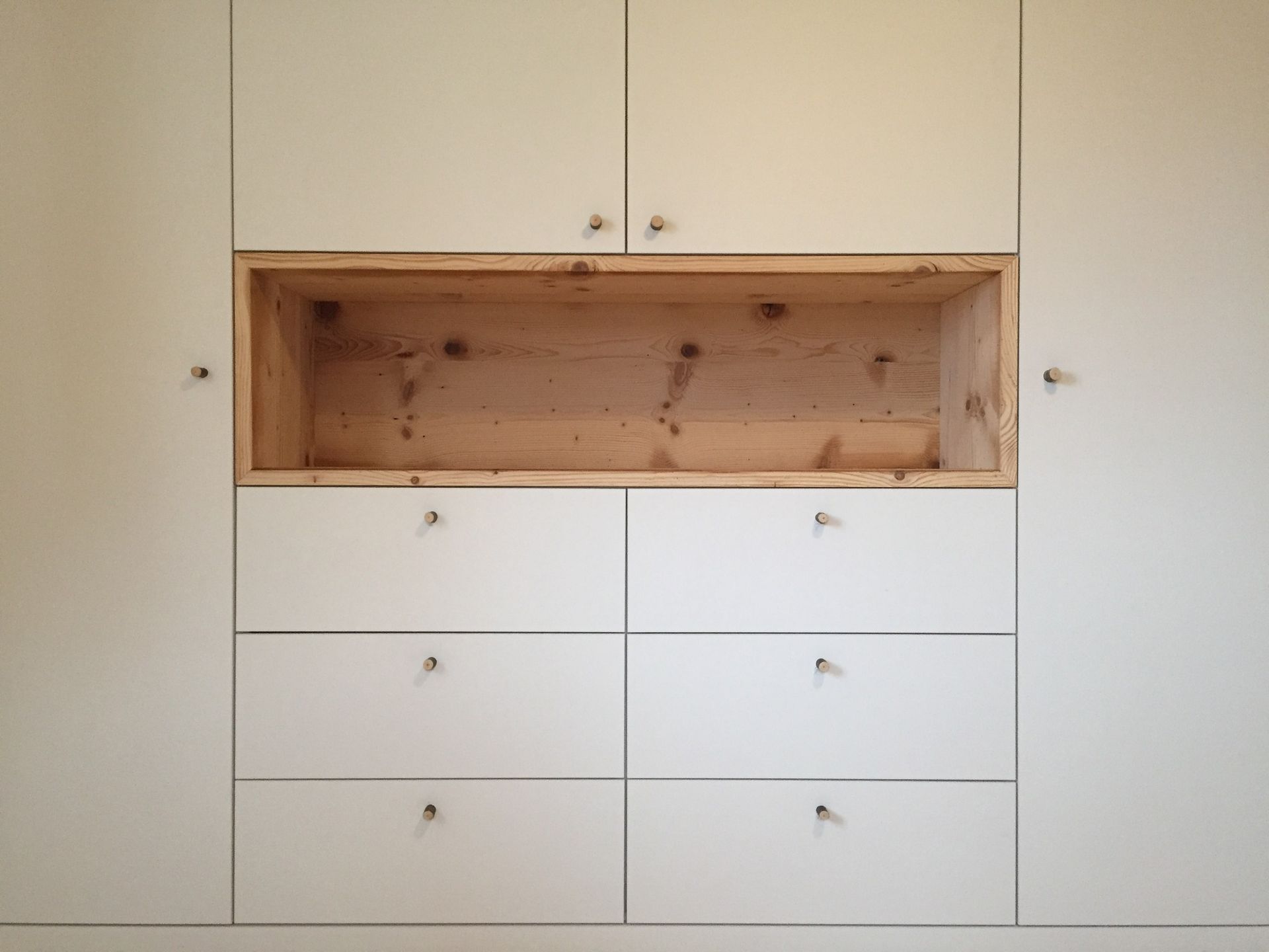 In der Mitte der Schränke befindet sich ein Holzregal.