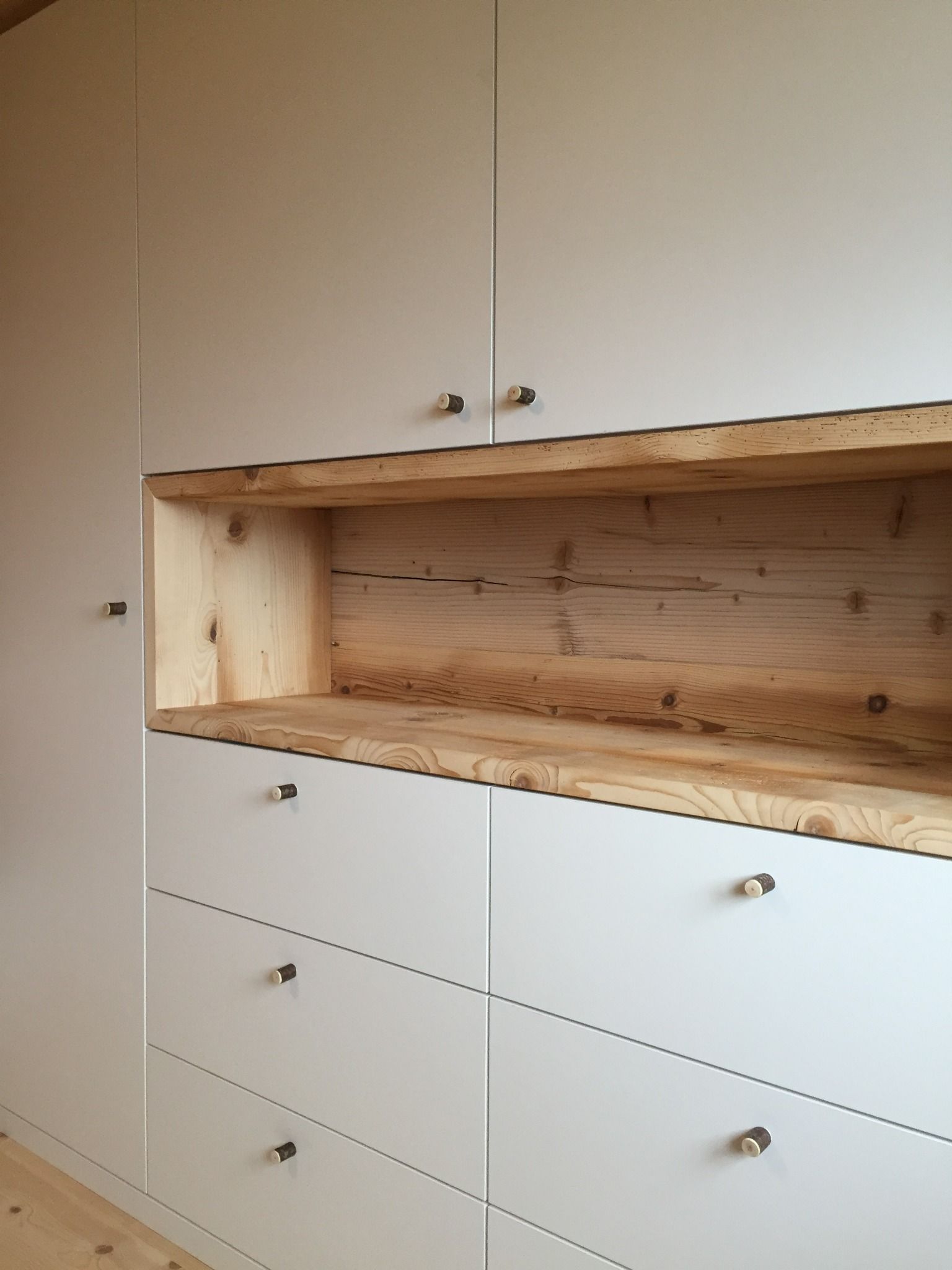 In der Mitte der Schränke befindet sich ein Holzregal.