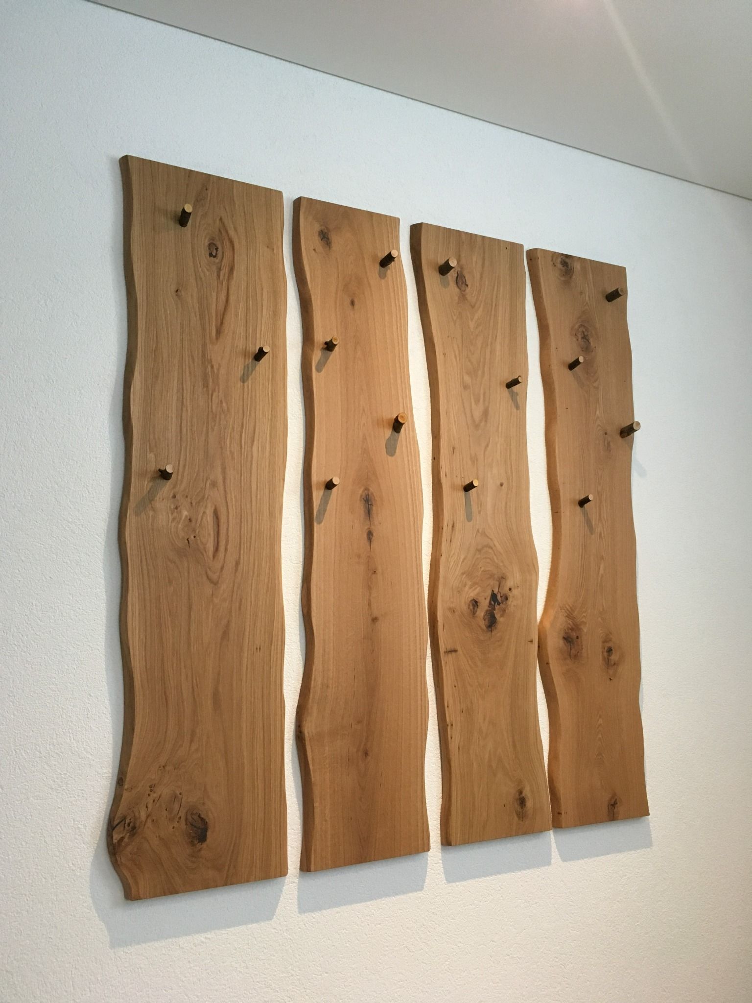 An einer weißen Wand hängen vier Holzbretter.