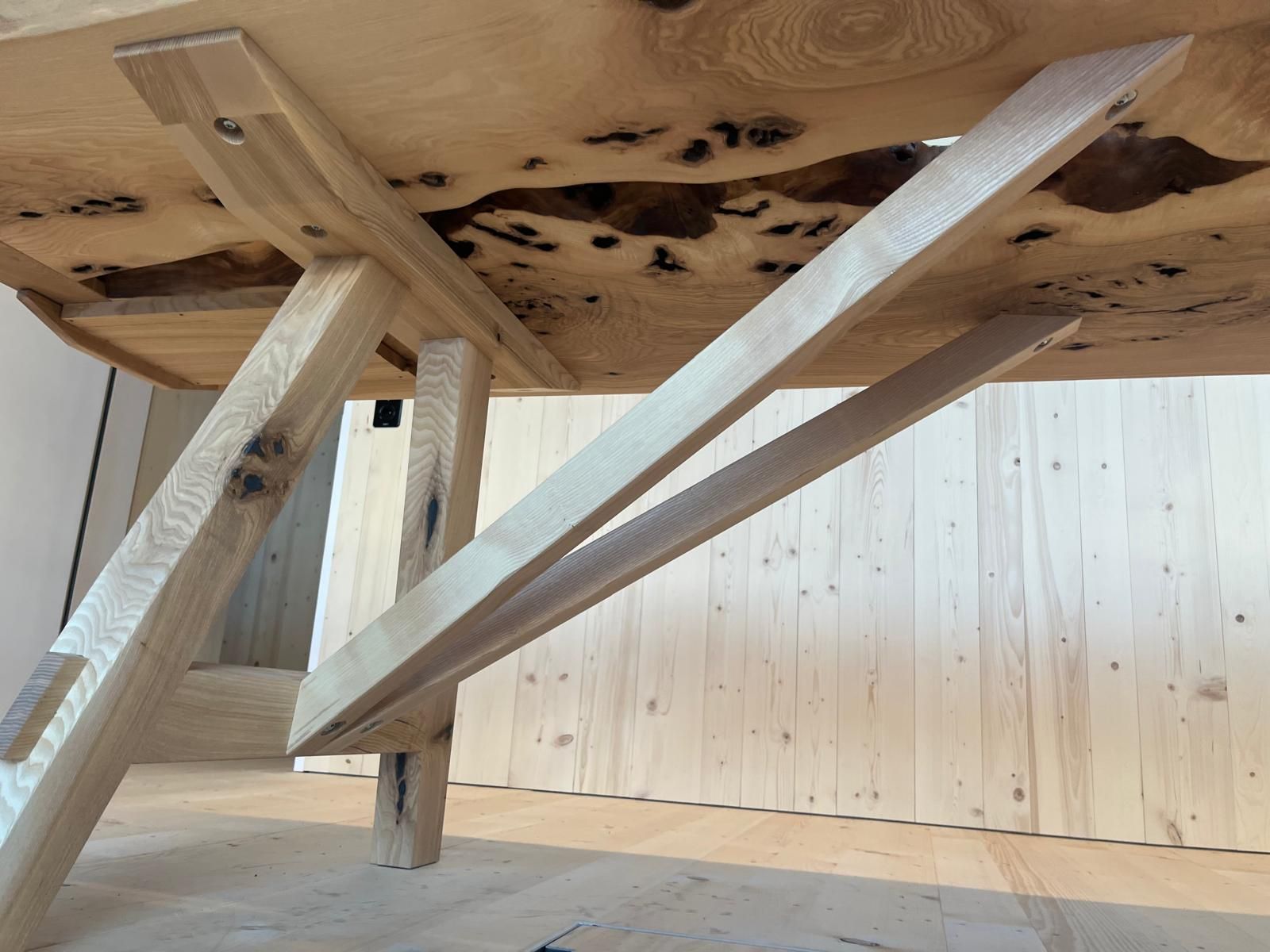 Die Unterseite eines Holztisches mit einer Holzwand im Hintergrund