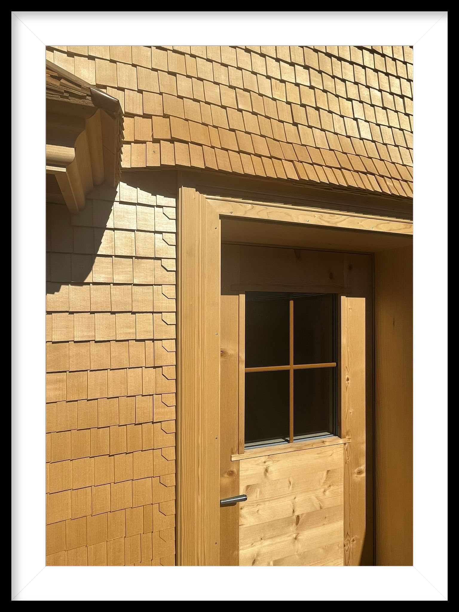 Ein Bild eines Holzgebäudes mit einer Tür und einem Fenster