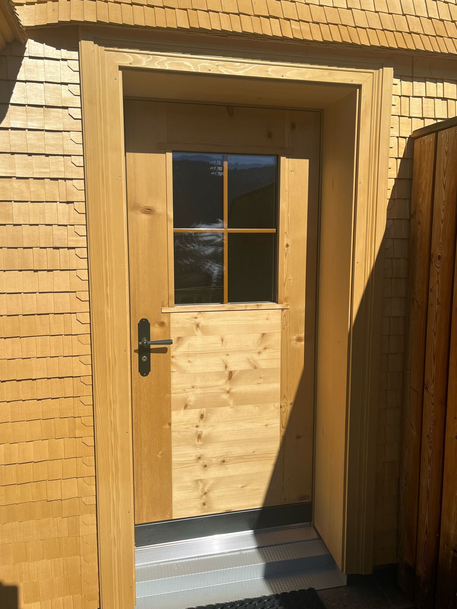 Eine Holztür mit einem Fenster an der Seite eines Gebäudes