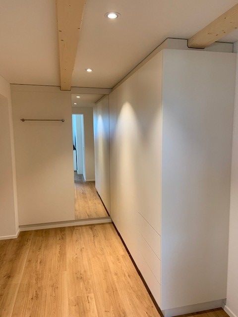 Ein Flur mit Hartholzboden und einem großen Spiegel an der Wand.