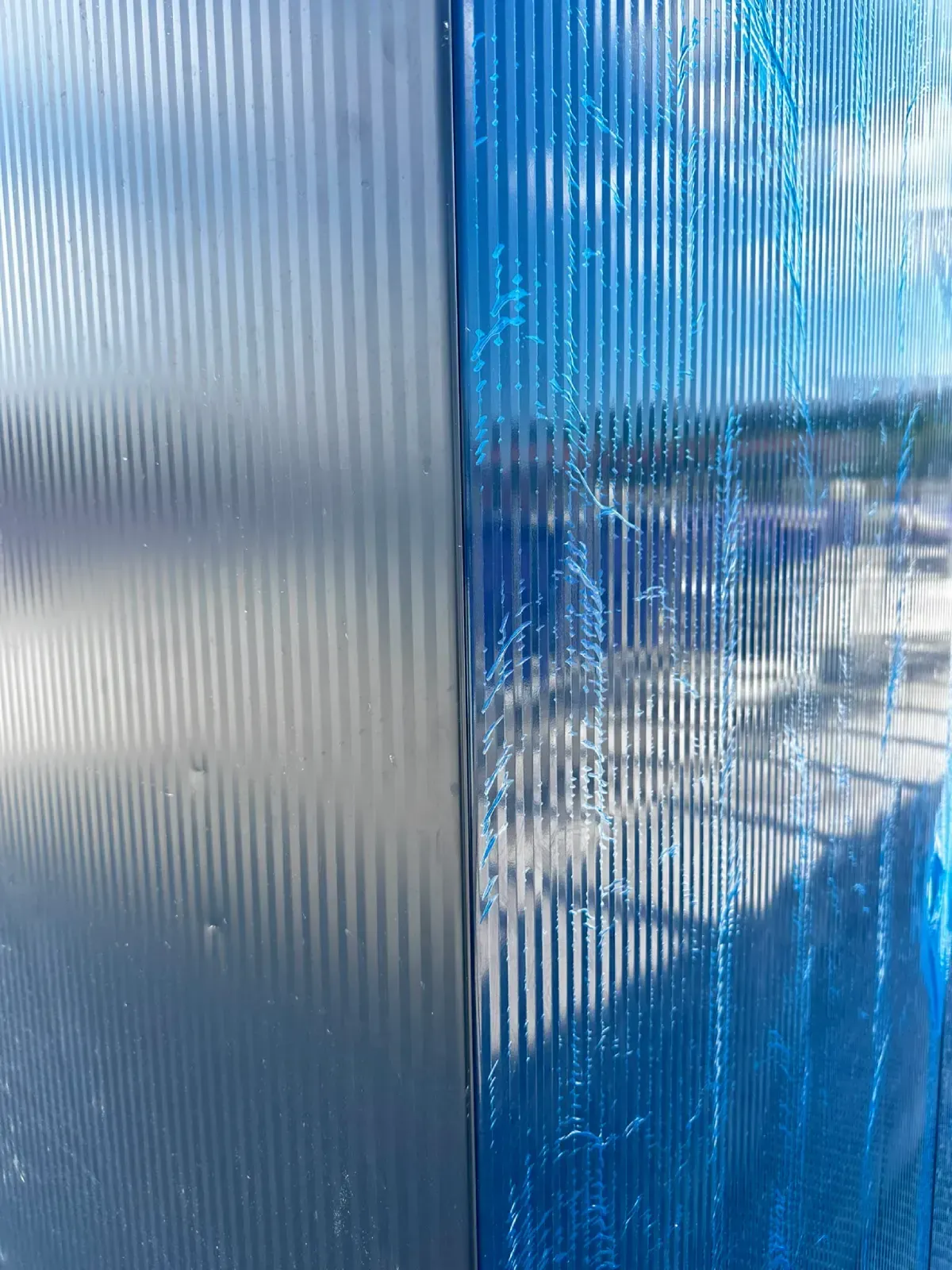 Paneles de plástico corrugado azul y transparente con luz solar y paisaje nevado visibles a través de ellos.