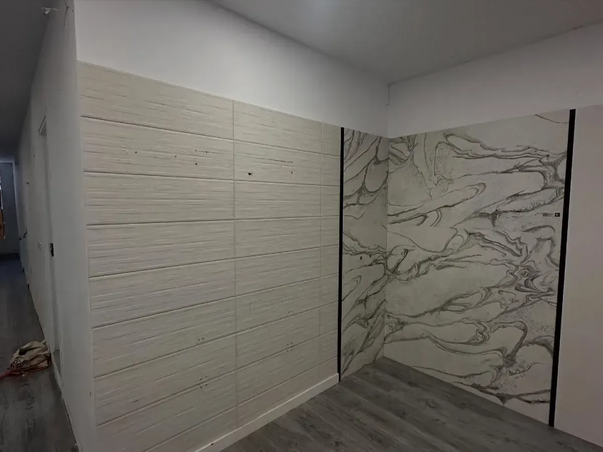 Pasillo interior moderno con paneles de pared de madera clara y una gran pared decorativa de mármol gris y blanco.