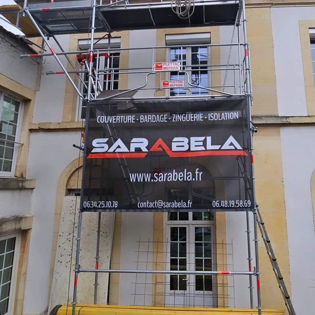 Échafaudages devant un bâtiment avec une banderole portant l'inscription « SARABELA » et l'adresse de leur site web.