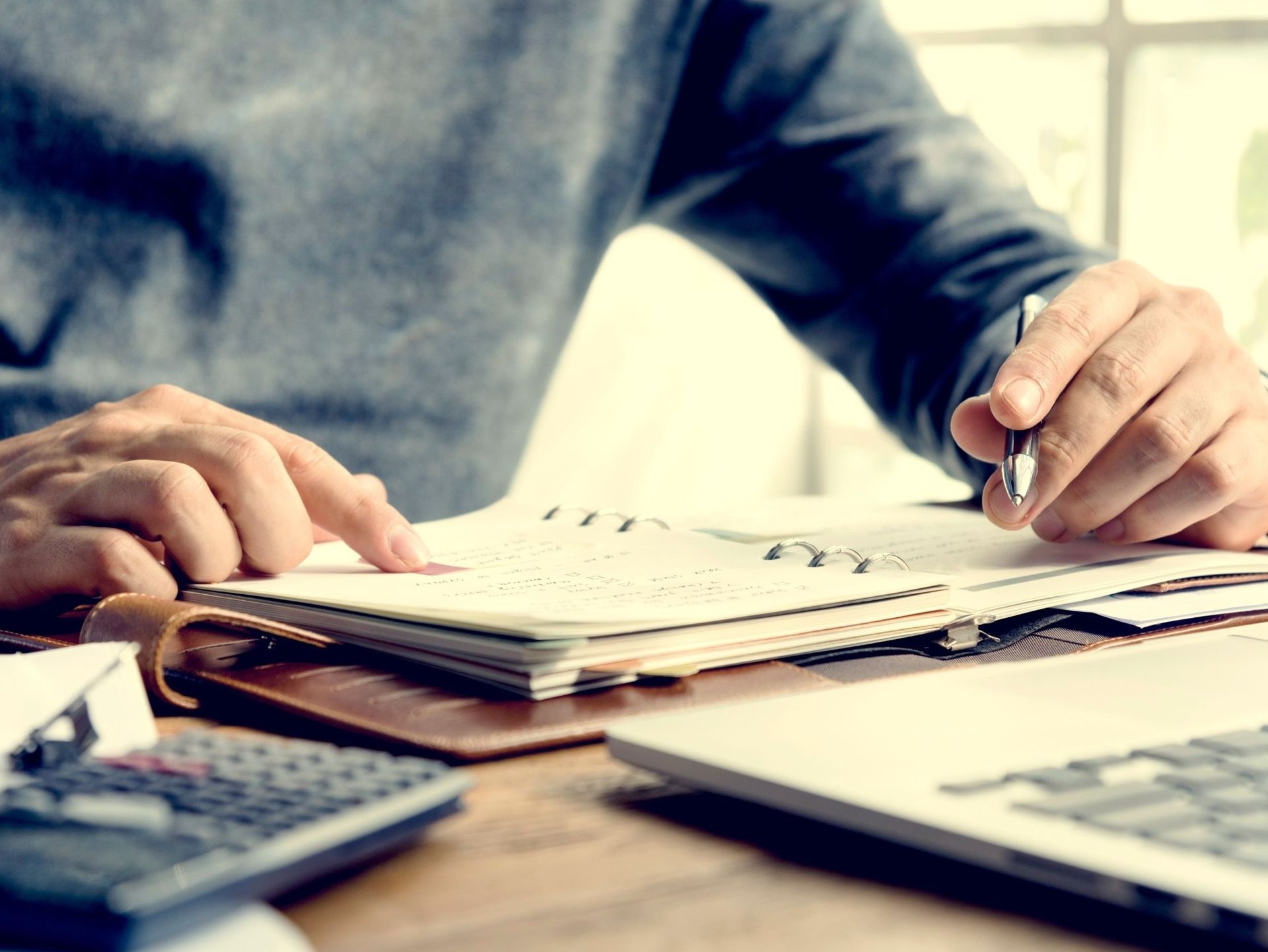 Un hombre está sentado en un escritorio escribiendo en un cuaderno.