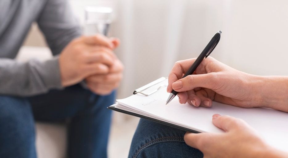 Una persona está escribiendo en un portapapeles mientras habla con otra persona.