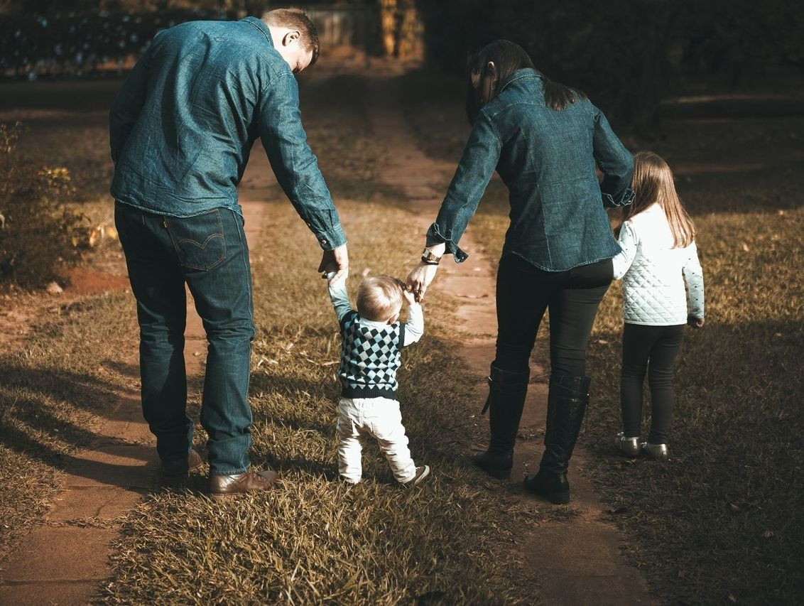 Una familia camina por un sendero tomados de la mano.