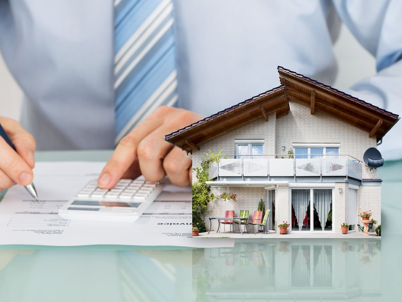 Un hombre está usando una calculadora al lado de una casa modelo.