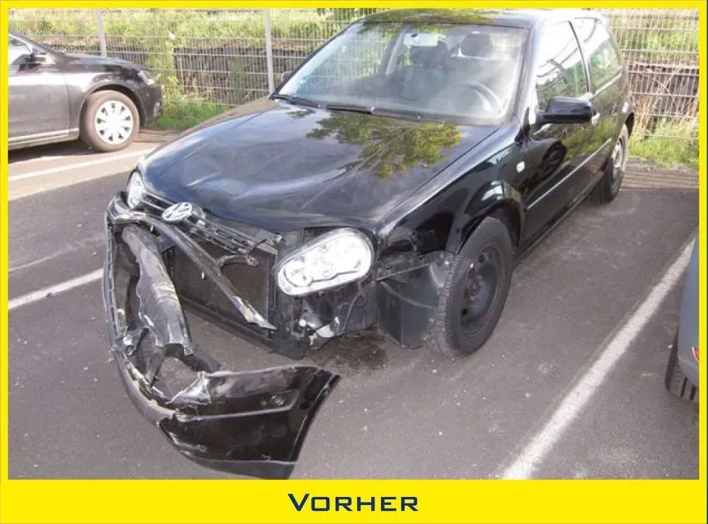 Ein schwarzer Volkswagen Golf mit schweren Frontschäden, darunter eine abgelöste Stoßstange, stand im Freien.
