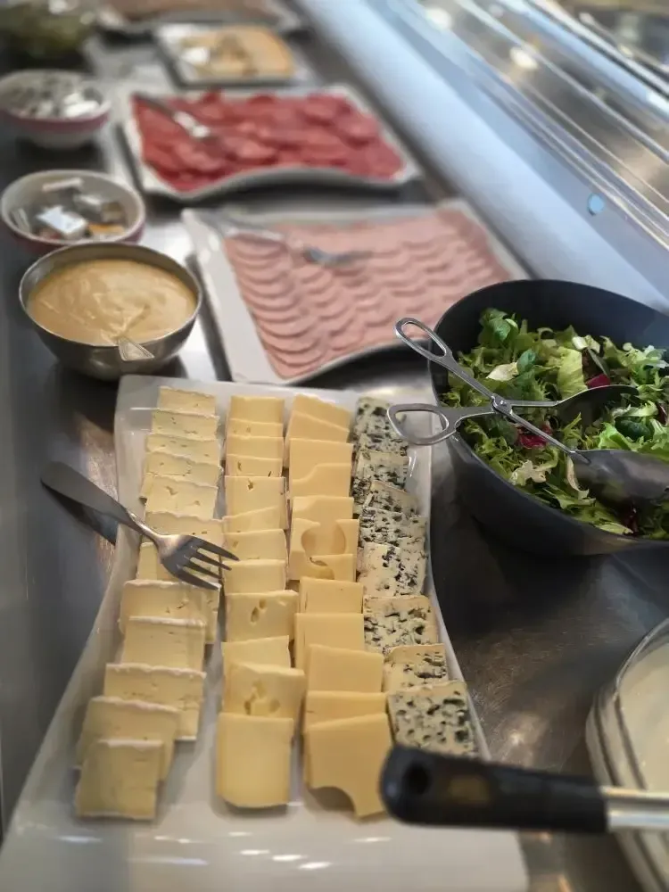 Une table chargée de plats du Moyen-Orient : pâtisseries farcies, salades, fruits et viandes.