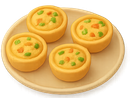 Quatre petits gâteaux jaunes en forme de muffin, accompagnés de légumes colorés, présentés dans une assiette beige.