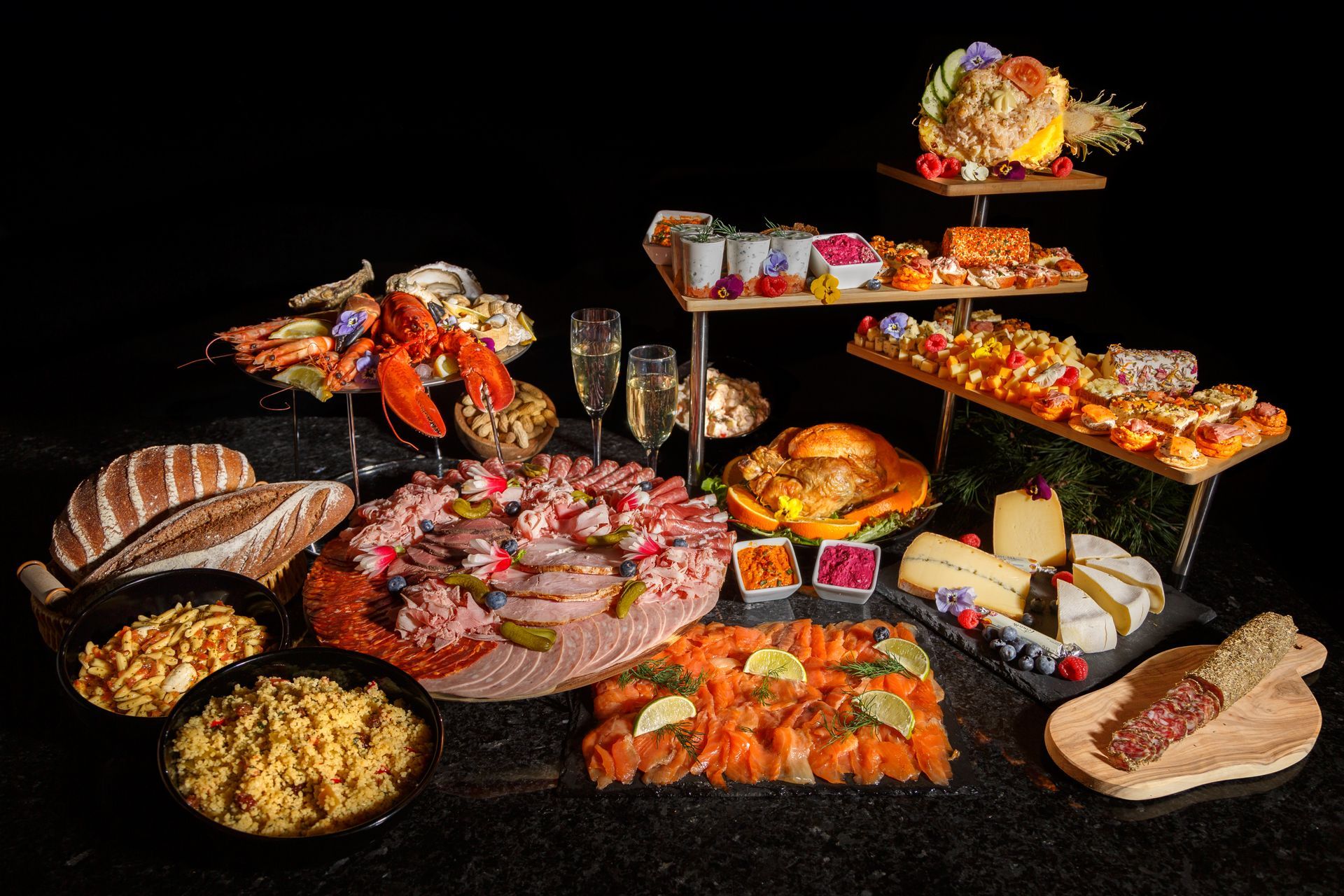 Buffet de fruits de mer, fromages, pains et amuse-gueules sur une surface noire.