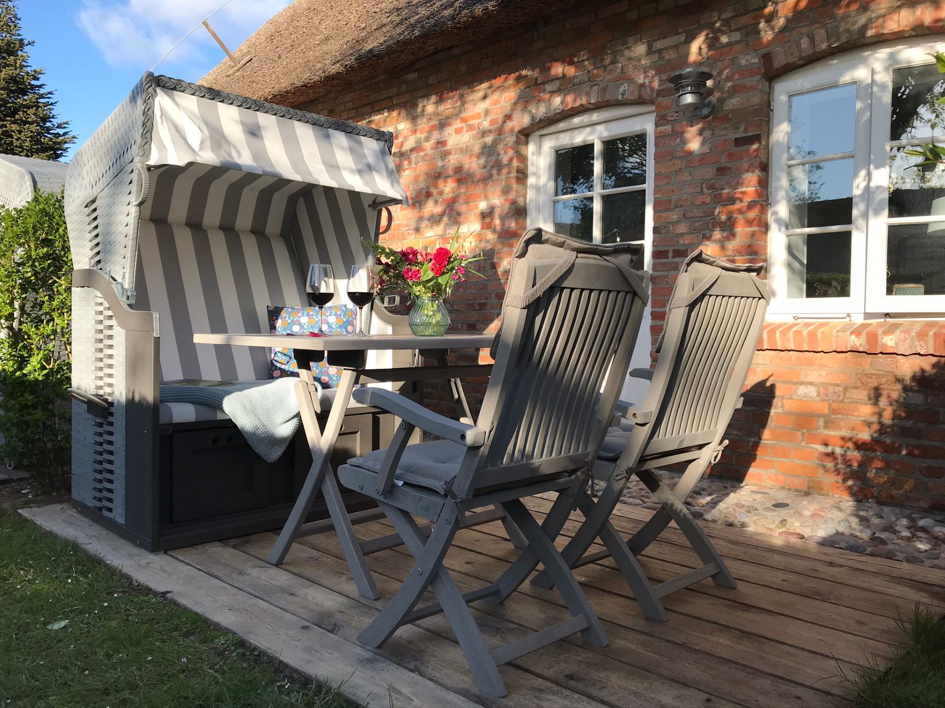 Auf der eigenen Terrasse, die direkt an das Wohnzimmer grenzt, genießen Sie ihre Mahlzeiten und ruhige Momente. Ermöglicht wird dies durch den eigenen Strandkorb mit passendem Tisch und Stühlen.