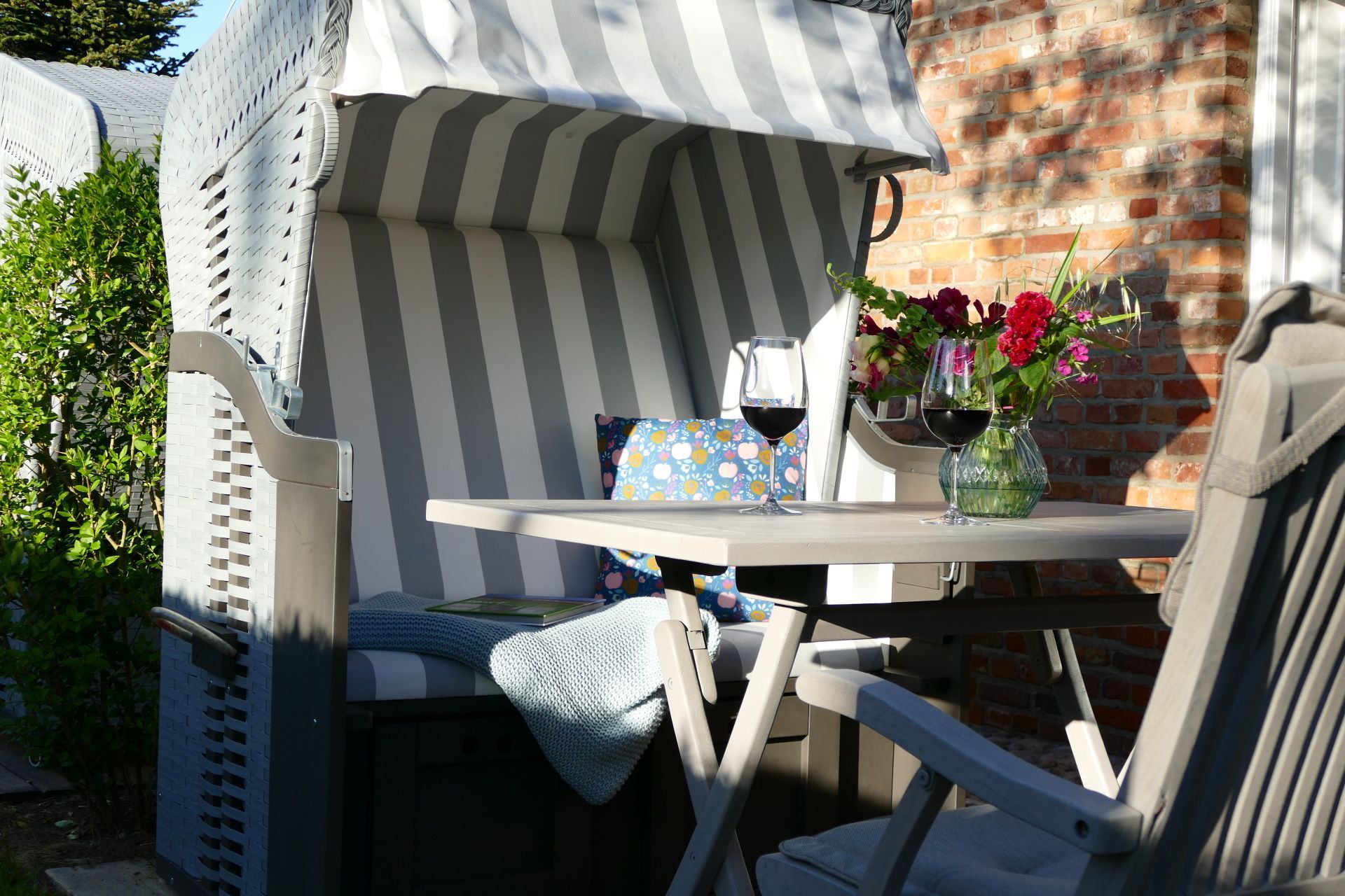 Auf der eigenen Terrasse, die direkt an das Wohnzimmer grenzt, genießen Sie ihre Mahlzeiten und ruhige Momente. Ermöglicht wird dies durch den eigenen Strandkorb mit passendem Tisch und Stühlen.