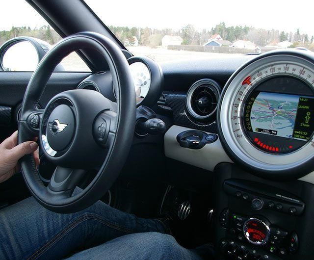 Una persona conduce un mini cooper con un mapa en el tablero