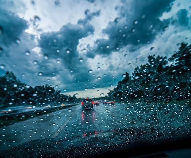 Un coche circula por una autopista bajo la lluvia.