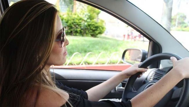 Una mujer que lleva gafas de sol conduce un coche.