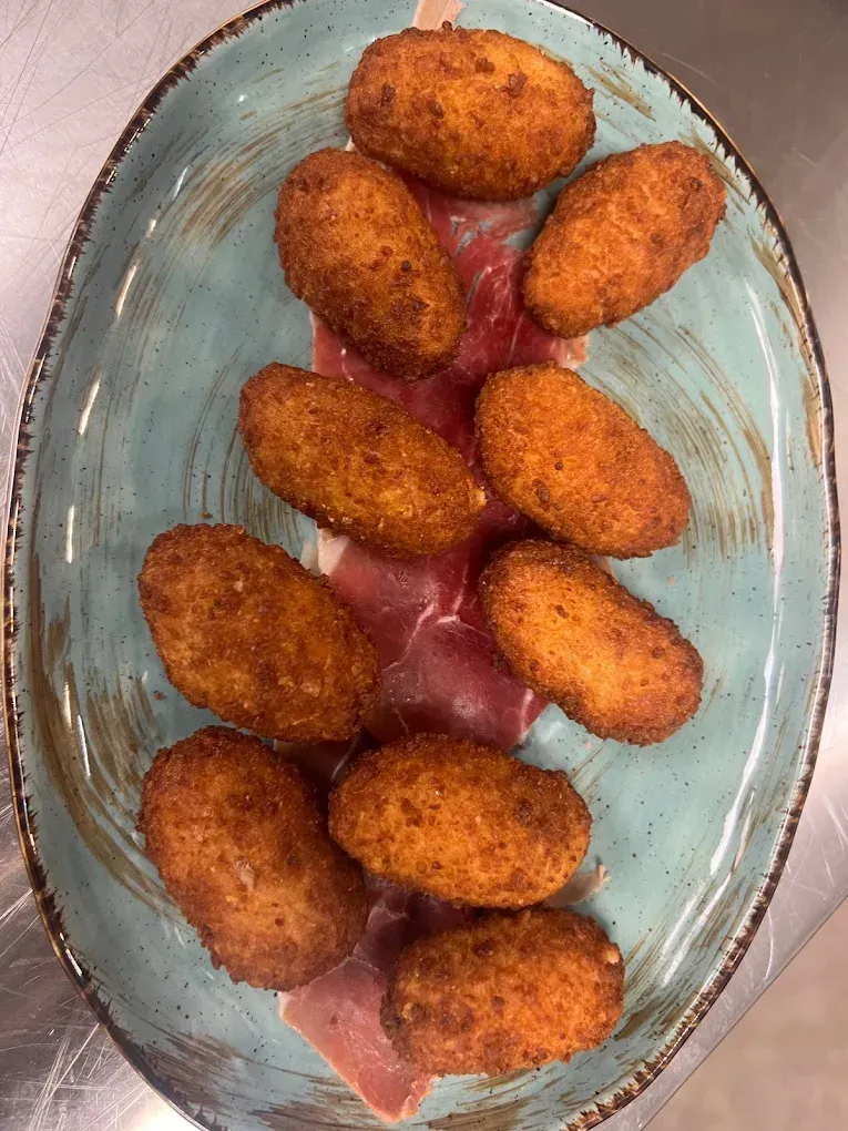 Un plato azul cubierto con comida frita sobre una mesa.