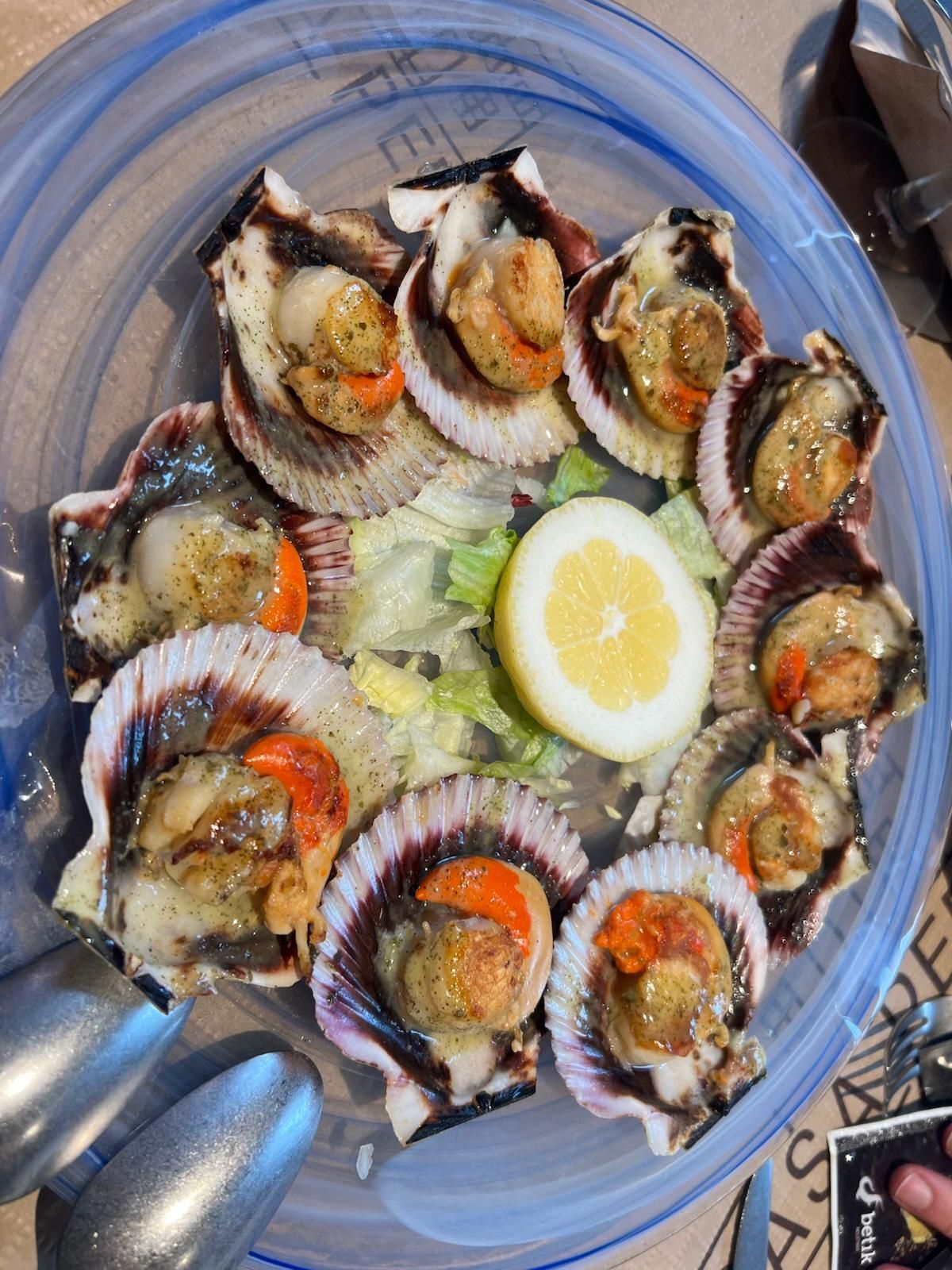 Un plato de vieiras con limón y lechuga.