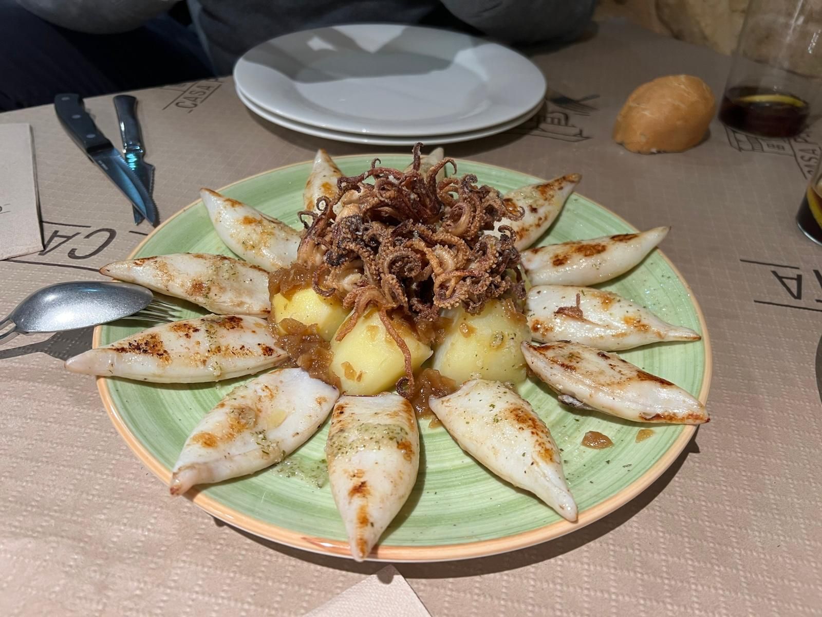 Un plato de comida con calamares y patatas en una mesa.