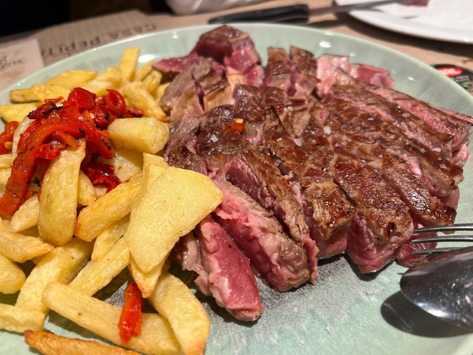 Un plato de carne y patatas fritas en una mesa.