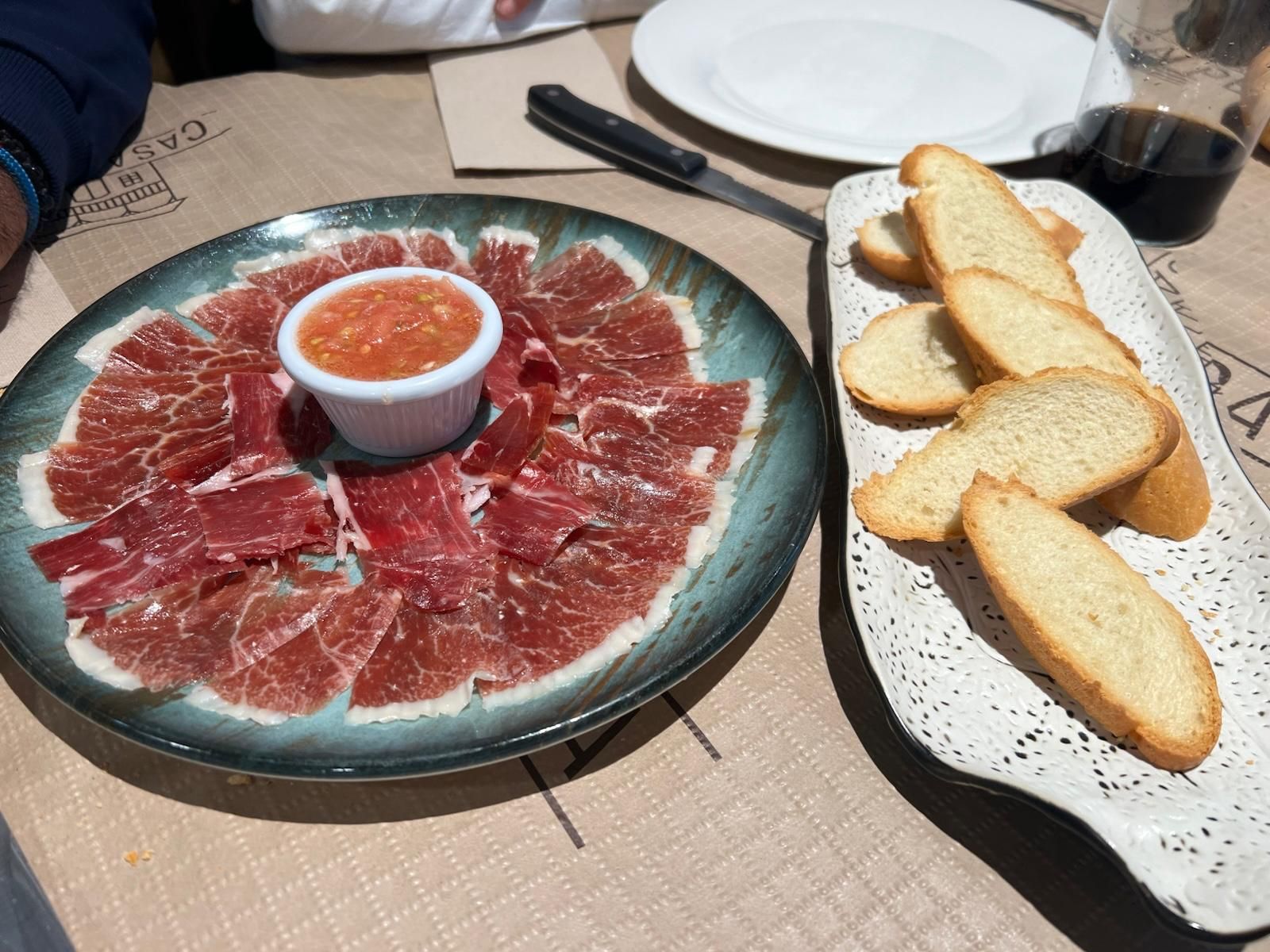 Un plato de carne al lado de un plato de pan sobre una mesa.