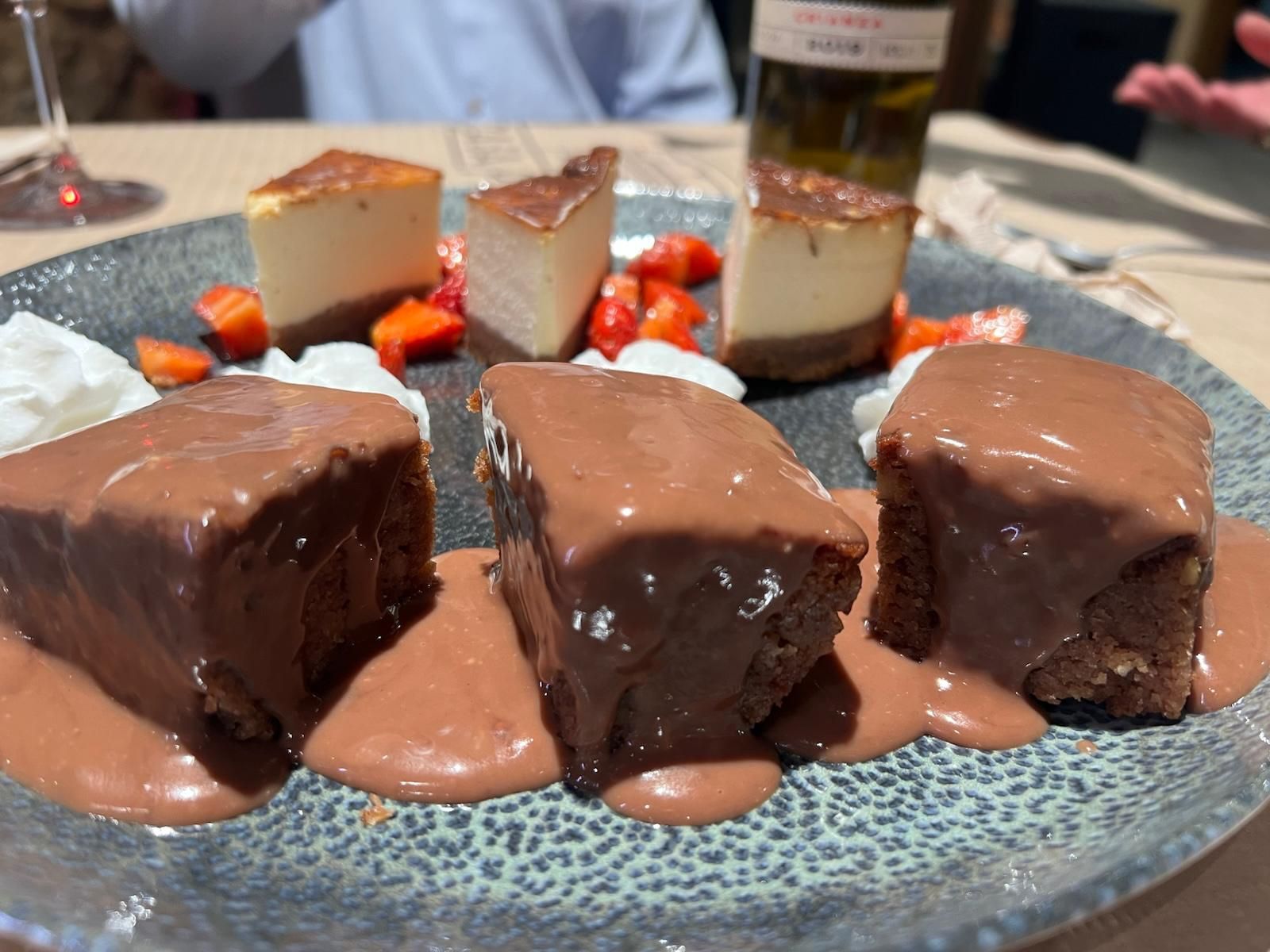 Un plato de postres con salsa de chocolate y fresas sobre una mesa.
