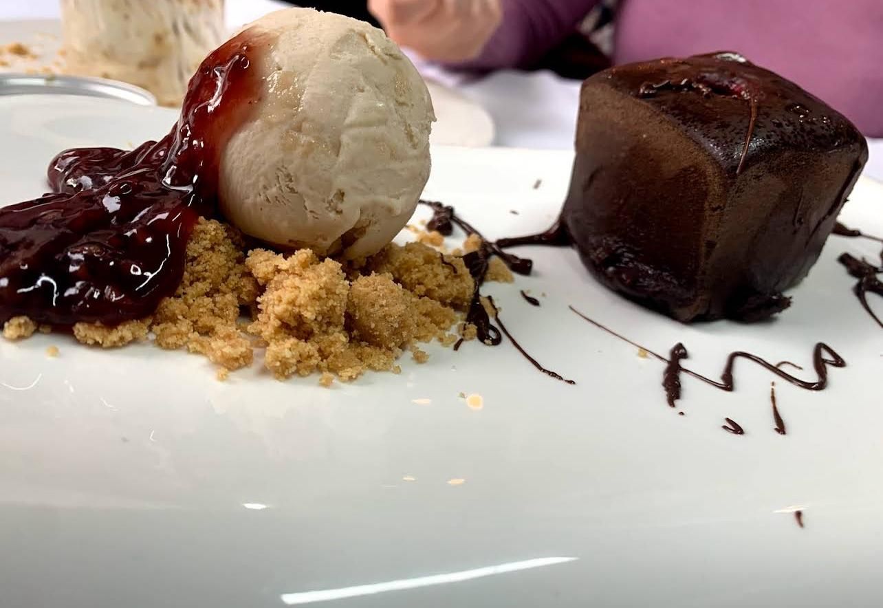 Un plato blanco cubierto con helado y un pastel de chocolate.