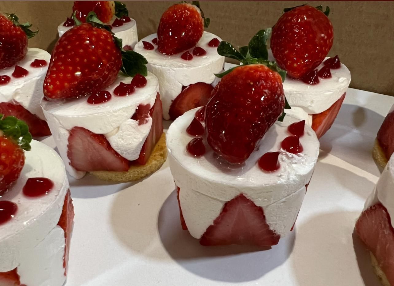 Un plato blanco cubierto con cupcakes con fresas encima.