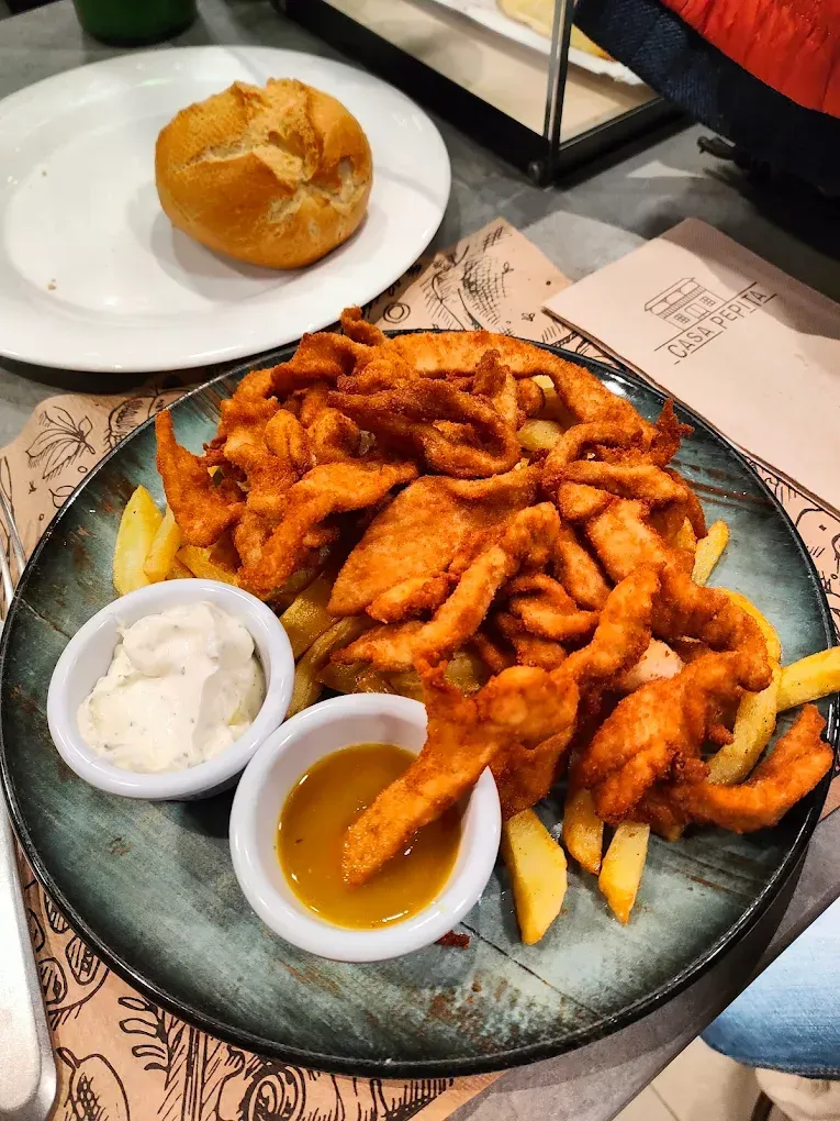 Un plato de comida con patatas fritas y salsa sobre una mesa.