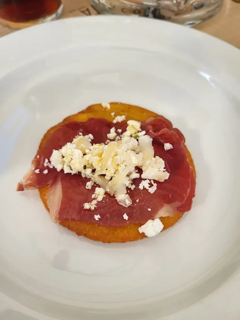 Un plato blanco cubierto con un trozo de carne y queso.