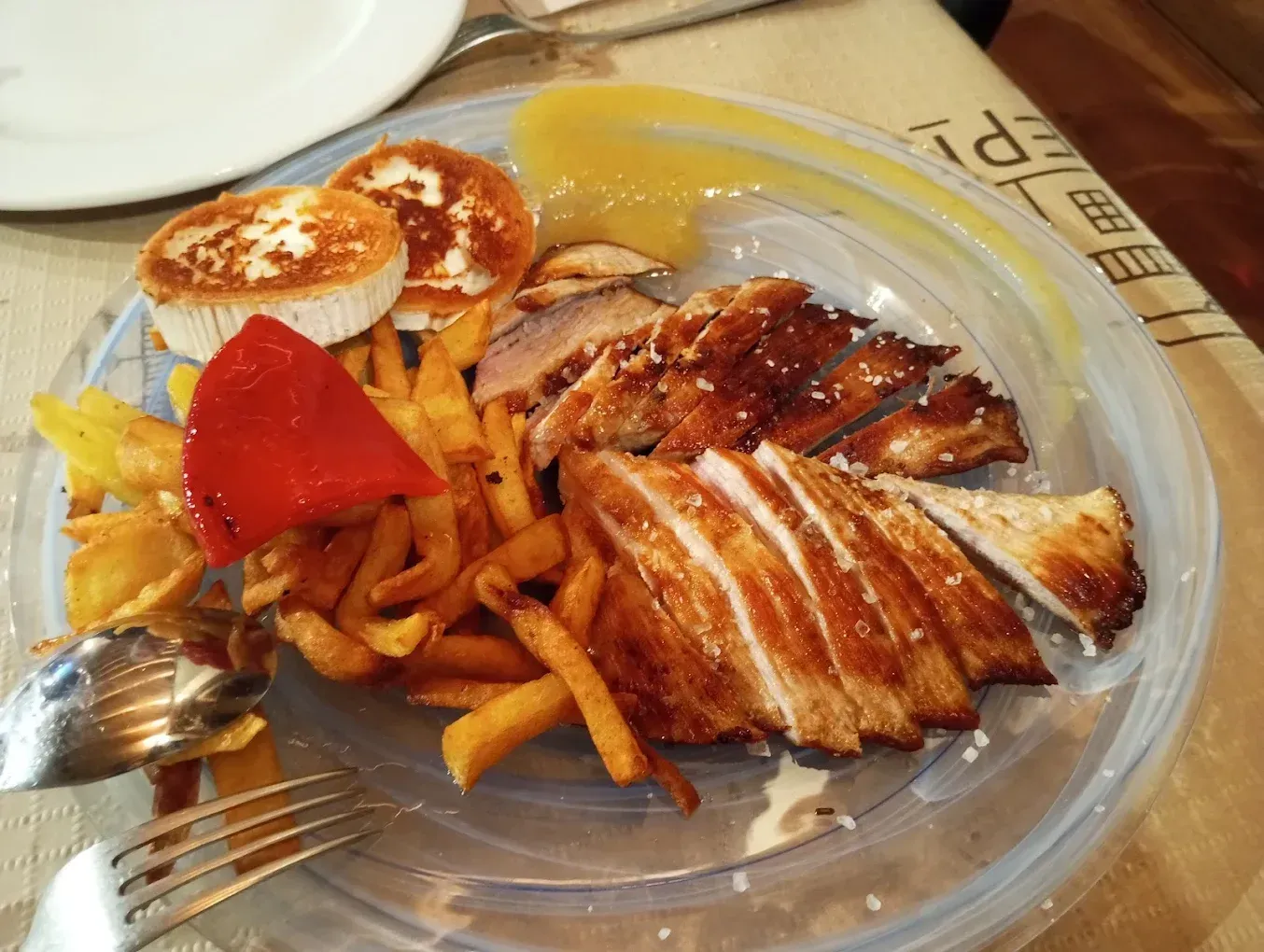 Un plato de comida con papas fritas y pollo en una mesa.