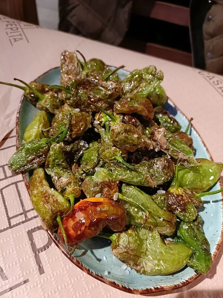 Un plato de pimientos fritos está sobre una mesa.