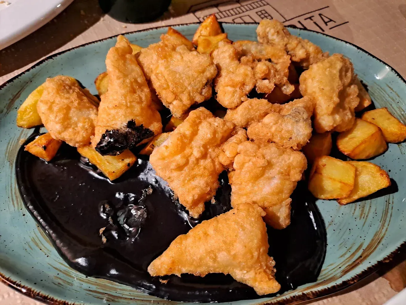 Un plato de comida con pollo frito y patatas en una mesa.