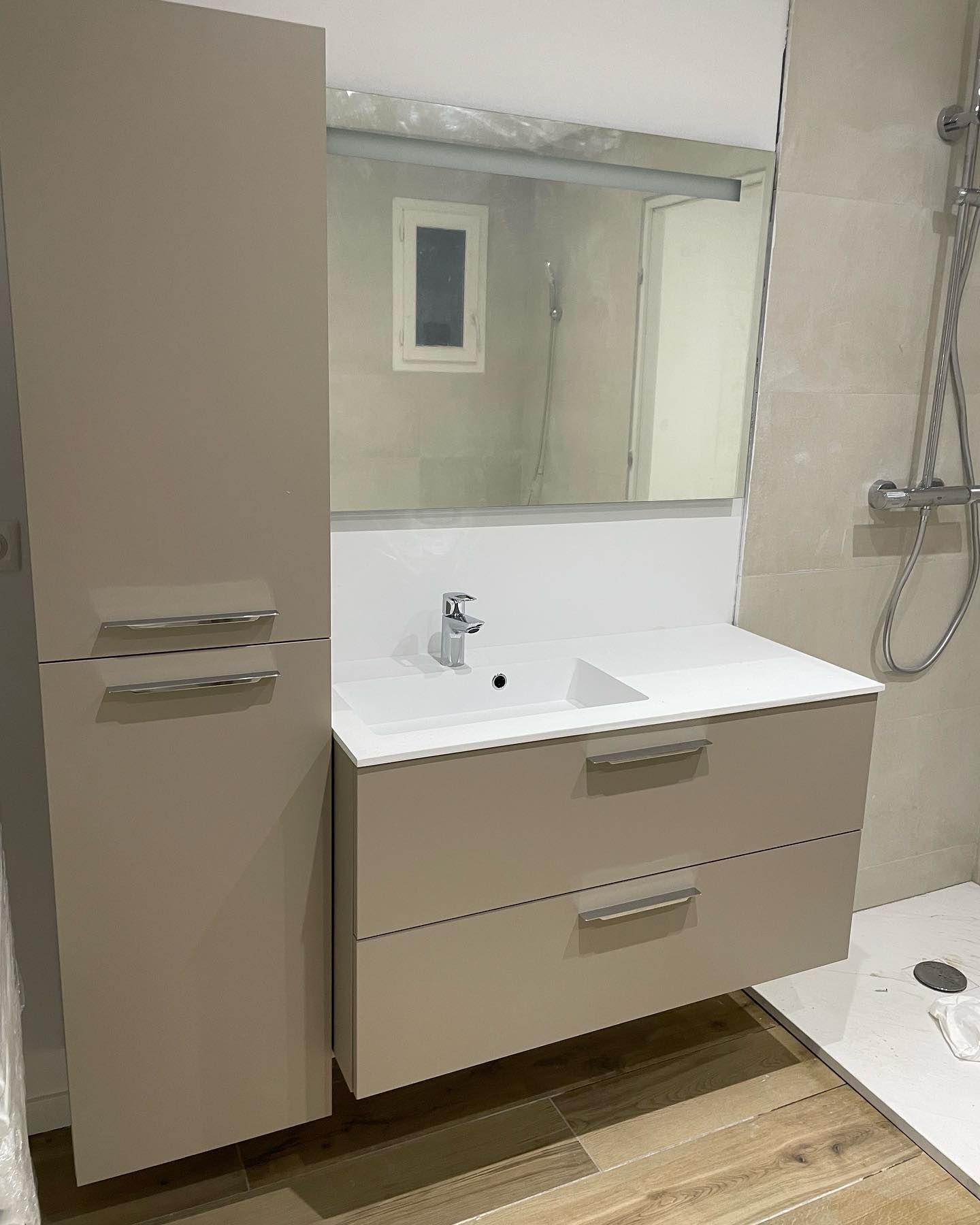 Photo qui représente un meuble de salle de bains et un miroir