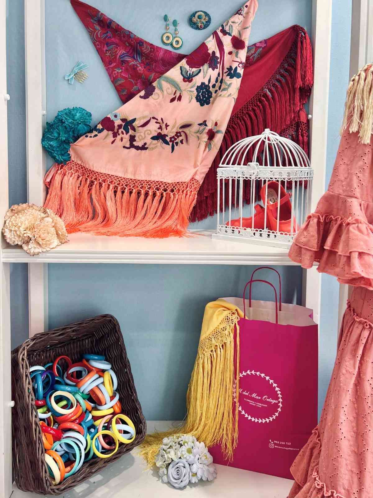 Estantería decorativa con bufandas coloridas, una jaula para pájaros, una cesta de lana, una bolsa de regalo y accesorios hechos a mano.