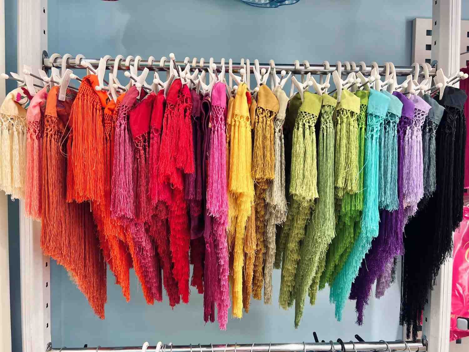 Hileras de coloridas muestras de tela con flecos colgadas en un expositor.
